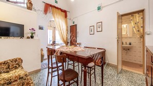 Un comedor con una mesa y sillas de madera, un televisor en la pared y una zona de cocina con un fregadero y armarios.