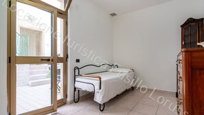 Un dormitorio con una cama, un armario de madera y un ventanal corredero que da a un espacio al aire libre.