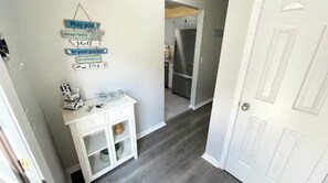 A hallway with a white cabinet, a wall-mounted sign, and a door leading to a kitchen area.