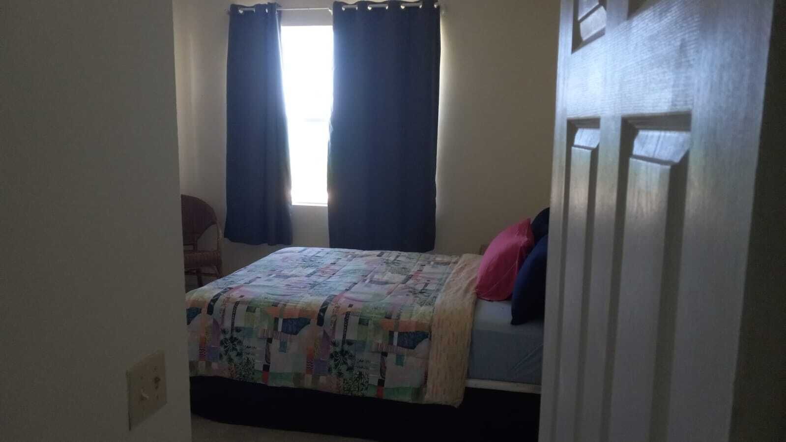 Une chambre à coucher avec un lit, une chaise et une fenêtre avec des rideaux.