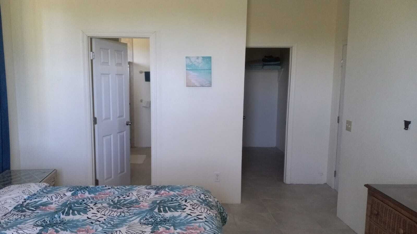 Een slaapkamer met een bed, een deur naar een gang en een kast.