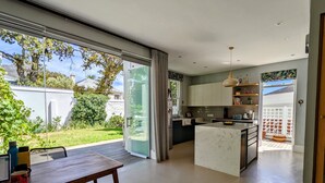 A modern kitchen with a large island, sliding glass doors to a patio, and a dining area with a table and chairs.