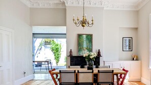 A dining area with a wooden table and chairs, a chandelier, and a painting on the wall.