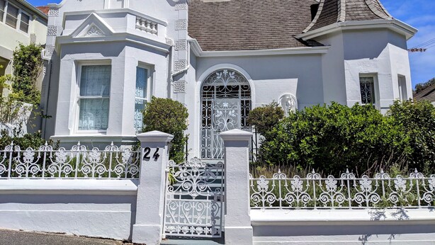 A Victorian-style house with a prominent turret and a gated entrance.