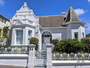 Une maison de style victorien, dotée d’une tourelle imposante et d’une entrée fermée par un portail.