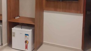 Quarto com televisão embutida, guarda-roupa e minibar.