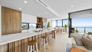A modern kitchen with a white countertop, wooden accents, and a view of the ocean. - Stunning Views just steps to Palm Beach (Palm Beach)