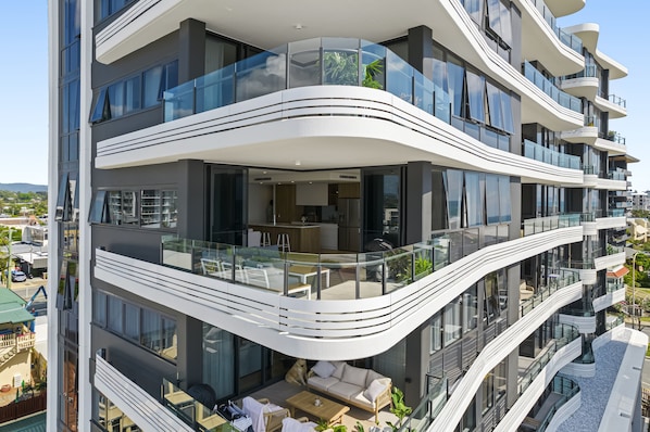 A multi-story building with balconies, large windows, and outdoor seating areas.