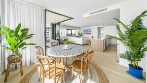 A modern living room with a round dining table, wooden chairs, and potted plants. - Stunning Views just steps to Palm Beach (Palm Beach)