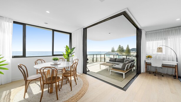 A modern living room with a large glass door leading to a balcony with a view of the sea. - Stunning Views just steps to Palm Beach (Palm Beach)