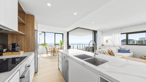 A modern kitchen with a large island, a dining area with a view, and a living space with a sofa and a view. - Stunning Views just steps to Palm Beach (Palm Beach)
