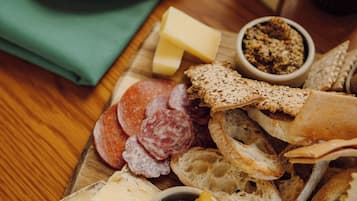 A wooden table with a variety of cheeses, bread, and charcuterie.