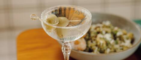 A martini glass with olives on a wooden table.