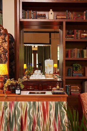 A room with a wooden desk, bookshelves, a mirror, and a patterned curtain.