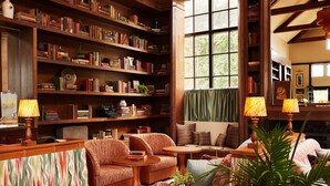 Ein gemütliches Lesezimmer mit Bücherregalen, Kamin und bequemen Sitzgelegenheiten.