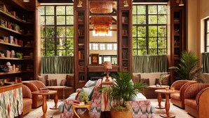 Ein gemütliches Bücherregal mit Regalen, einem Sofa, einem Couchtisch und einem großen Fenster mit Blick auf Bäume.