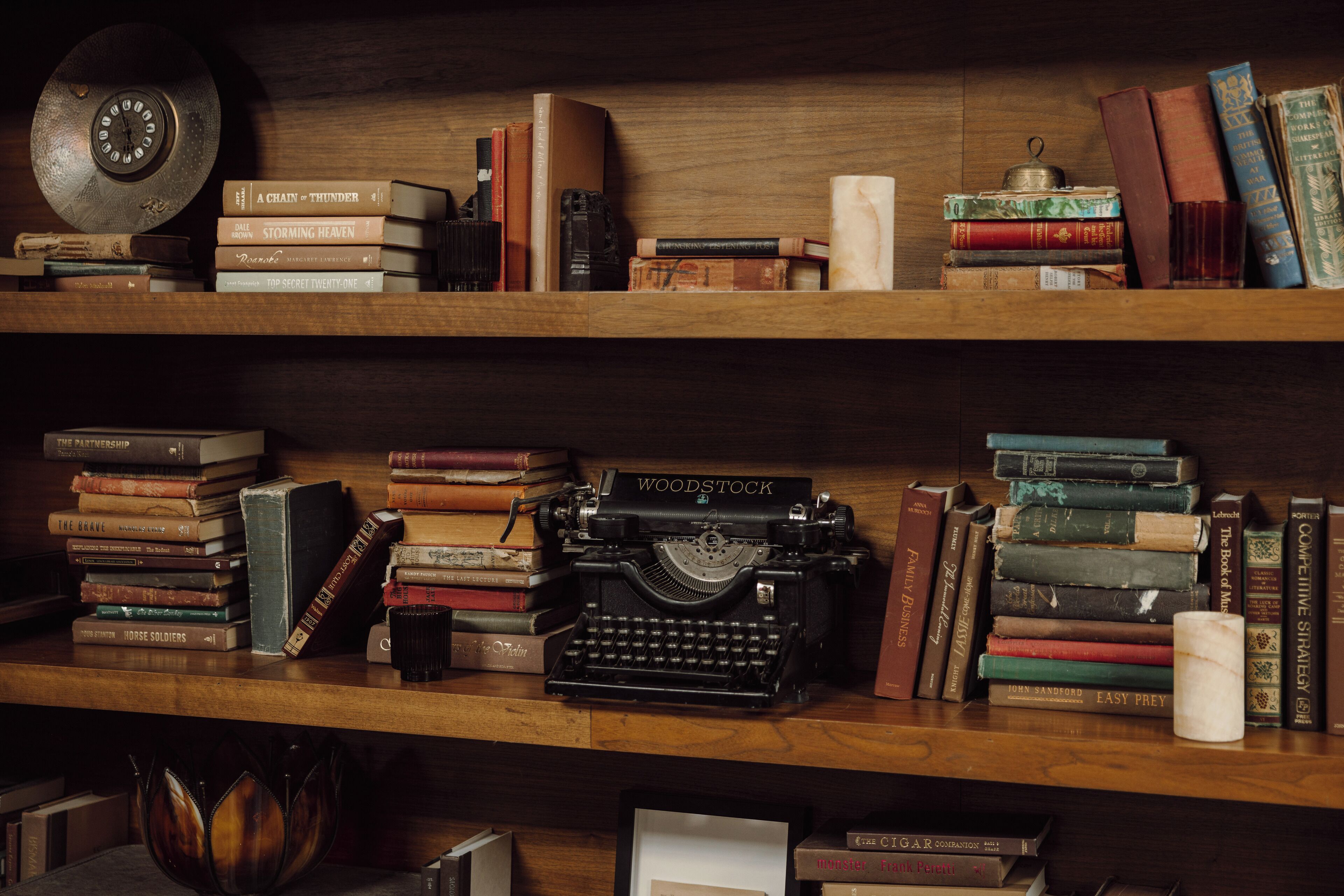A wooden bookshelf with various books and a vintage typewriter.