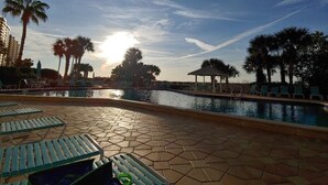 A pool area with lounge chairs, palm trees, and a gazebo. - Gorgeous beachfront studio penthouse! (Clearwater Beach)