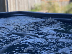 Relax in an outdoor hot tub surrounded by lush greenery.