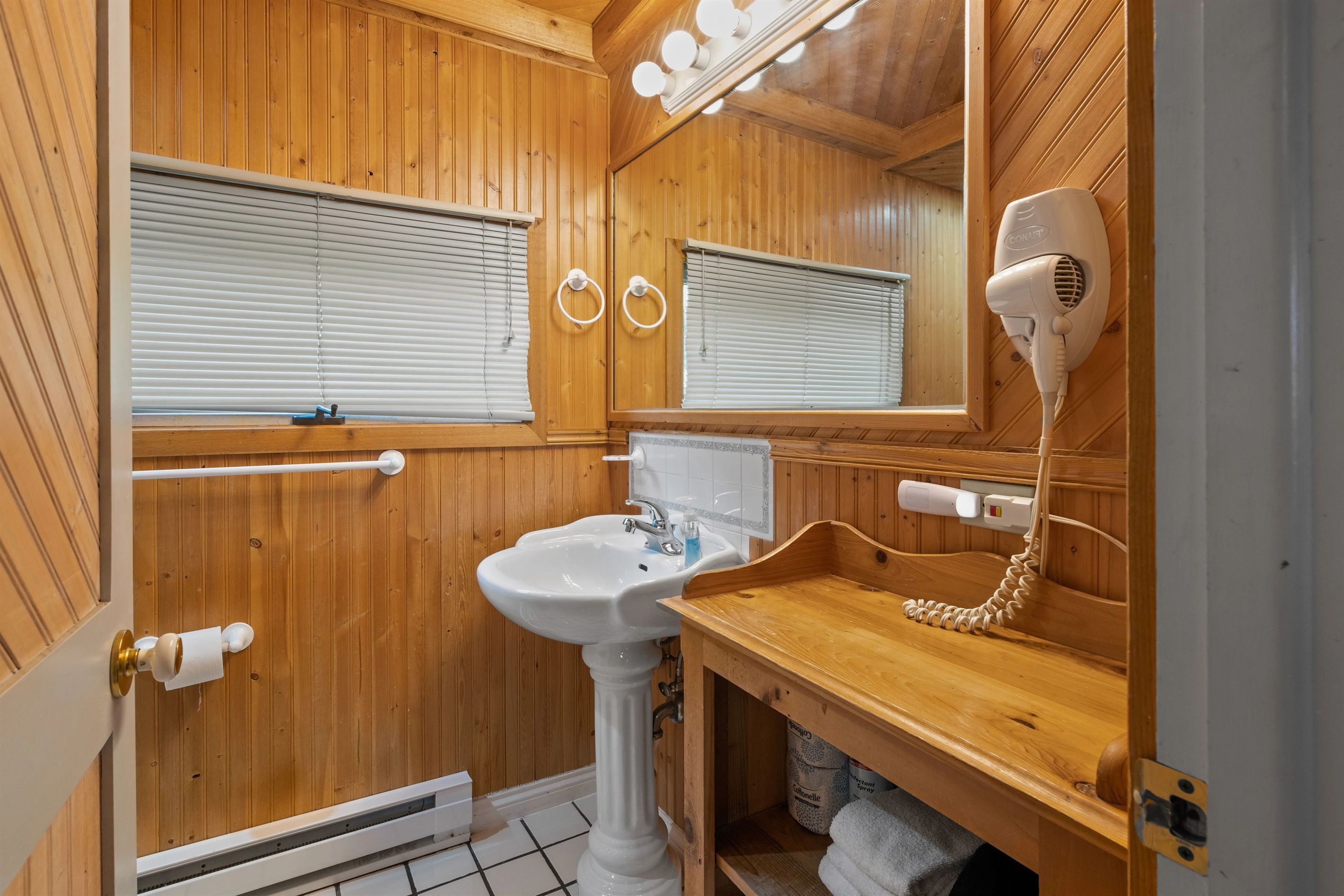 A wooden bathroom with a sink, mirror, and hairdryer.