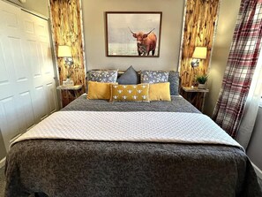 A bed with a patterned bedspread, two pillows, a framed picture on the wall, and a lamp on each side of the bed. - Journey's End-Pointe Royale Premiere Gated Resort (Branson)
