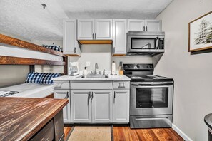 A compact kitchen with a built-in oven, microwave, and a coffee maker. - 23 Mountain Crest, Snowshoe, WV - Country Chic (Snowshoe)