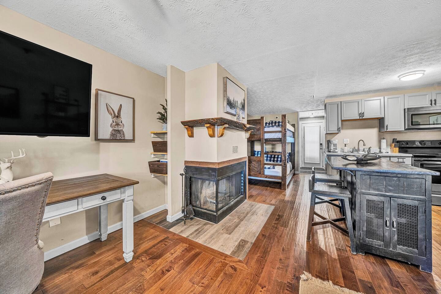 A modern kitchen with a built-in microwave, a dining area with a wooden table, and a fireplace with a mantel.