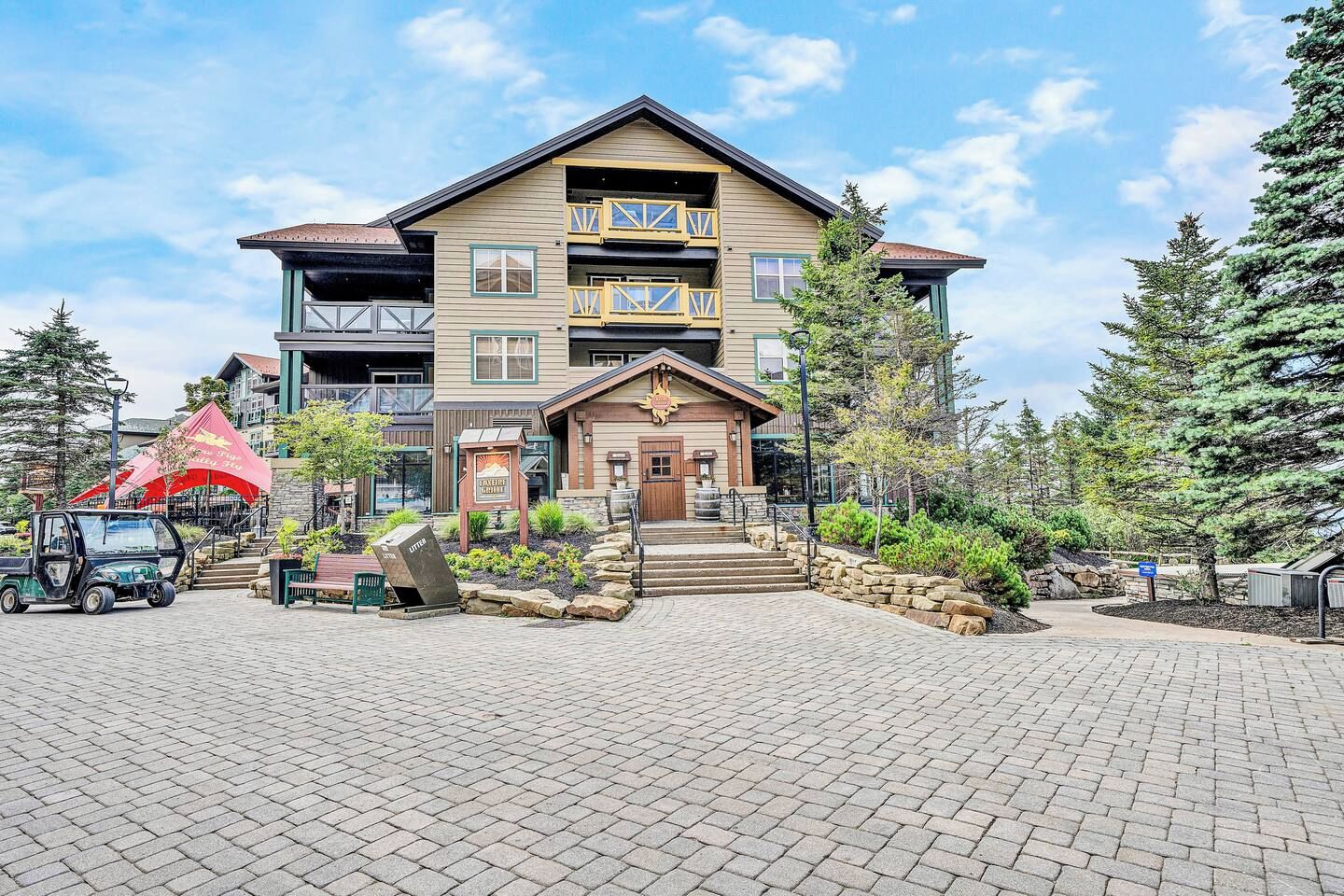 A multi-story hotel with a prominent entrance, a parking area, and a red canopy structure.