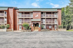 A multi-story building with a central entrance, balconies, and a sign indicating the number of units. - 23 Mountain Crest, Snowshoe, WV - Country Chic (Snowshoe)