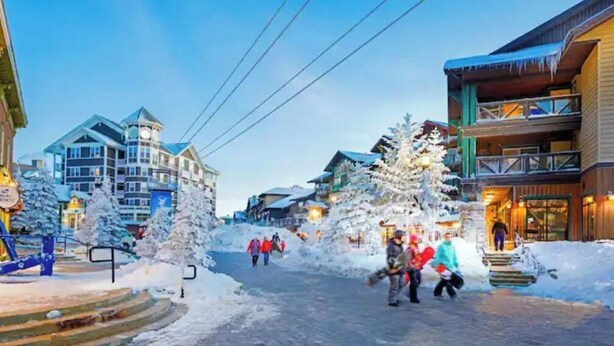 En snedækket gade med bygninger, heriblandt et fleretasagers hotel med balkoner og et ski-hotel.