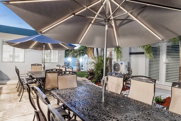 An outdoor patio with a metal table, chairs, and umbrellas.