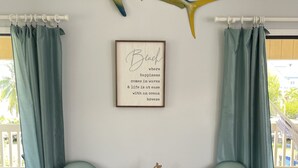 A room with two green chairs, a framed quote on the wall, a decorative fish, and a small table with a starfish ornament. - BeachHouse @ Sombrero & Ocean access w/45’ Dock, kayaks and Bikes. (Marathon)