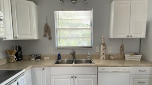 A kitchen with white cabinets, a stainless steel sink, and a window with blinds. - BeachHouse @ Sombrero & Ocean access w/45’ Dock, kayaks and Bikes. (Marathon)
