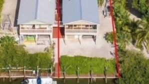 A waterfront property with a dock, a boat, and a building with a grey roof. - BeachHouse @ Sombrero & Ocean access w/45’ Dock, kayaks and Bikes. (Marathon)