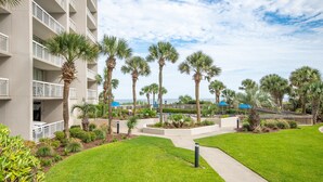 A hotel courtyard with palm trees, a pool, and a building with balconies. - Remodeled Studio-Ocnview-Steps2Beach-Kingston Plantation-Pool-Restaurant/Bar (Myrtle Beach)