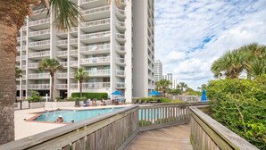 A multi-story hotel with balconies, a pool area, and a wooden deck. - Remodeled Studio-Ocnview-Steps2Beach-Kingston Plantation-Pool-Restaurant/Bar (Myrtle Beach)