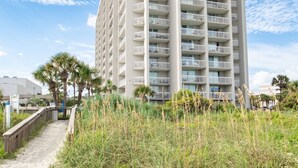 A tall, multi-story building with balconies, surrounded by sand and vegetation. - Remodeled Studio-Ocnview-Steps2Beach-Kingston Plantation-Pool-Restaurant/Bar (Myrtle Beach)