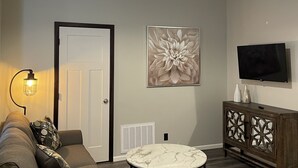A living room with a sofa, a coffee table, a TV, and a door. - 1 of 3 NEW, NEW, NEW!  Downtown Wabasha Studio - Unit #100 113 Pembroke Ave. (Wabasha)