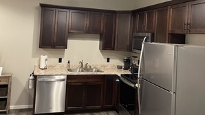 A modern kitchen with dark wooden cabinets, stainless steel appliances, and a ceiling fan. - 1 of 3 NEW, NEW, NEW!  Downtown Wabasha Studio - Unit #100 113 Pembroke Ave. (Wabasha)