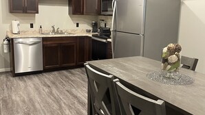 A modern kitchen with dark wood cabinets, stainless steel appliances, and a wooden dining table with chairs. - 1 of 3 NEW, NEW, NEW!  Downtown Wabasha Studio - Unit #100 113 Pembroke Ave. (Wabasha)