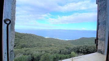 Une vue depuis une fenêtre donnant sur un paysage côtier, avec un ciel dégagé.