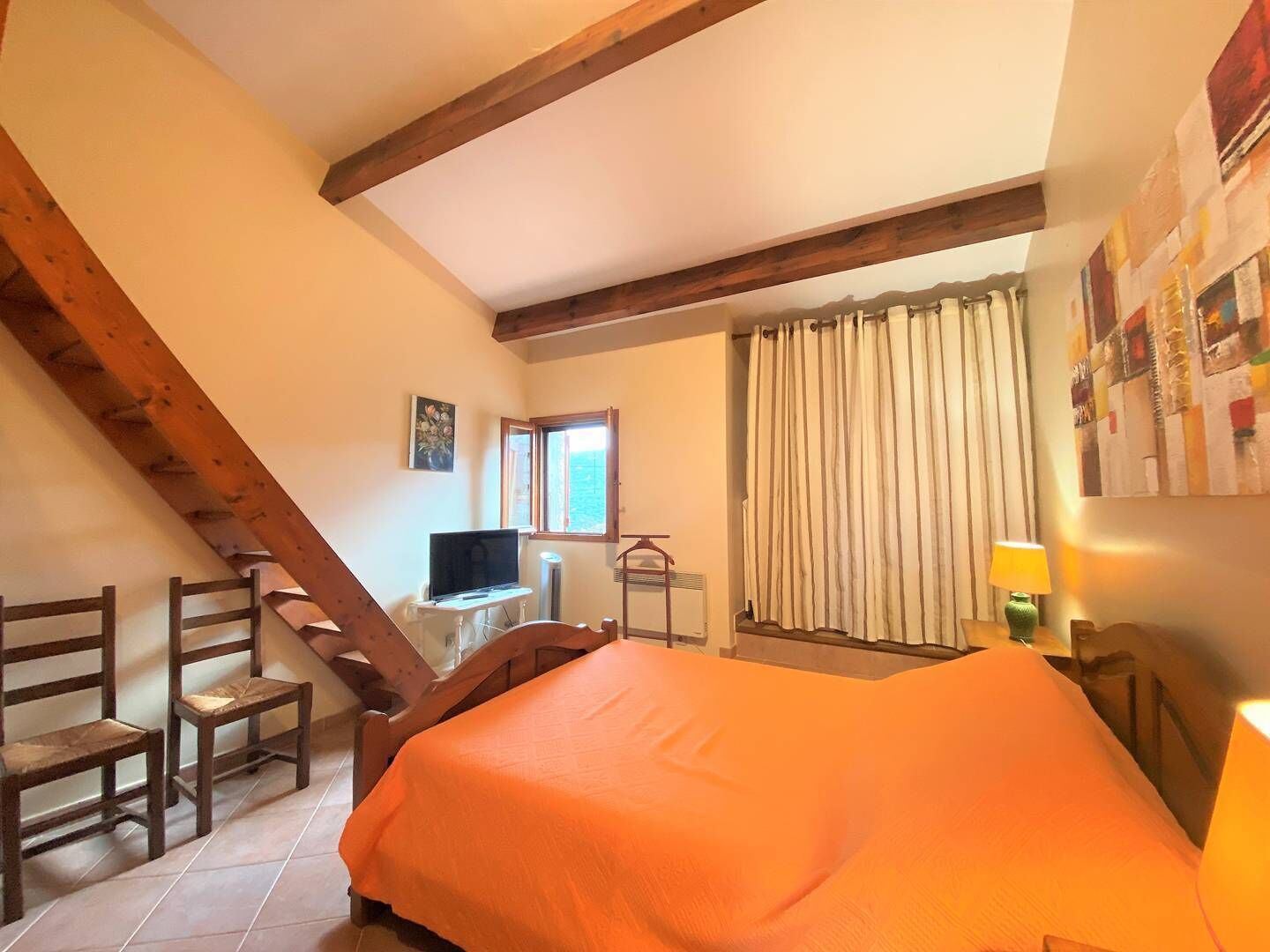 Una camera da letto con un letto, una TV, una finestra e vista sul mare.