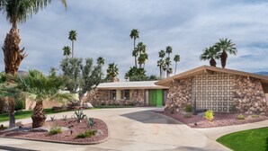 A house with a stone facade, a green door, and a driveway leading to a garage. - Fully furnished Midcentury Home, 3 Bd/Den, Views, Best So PD Location (Palm Desert)