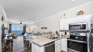 A modern kitchen with white cabinets, stainless steel appliances, and a granite countertop. - Beach Front Condo! Newly Renovated! Awesome views! Private Balcony! (Gulf Shores)