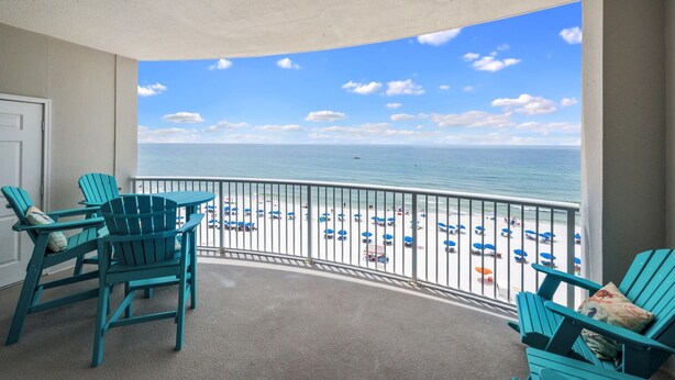 A balcony with teal Adirondack chairs, a view of the beach, and a railing. - Beach Front Condo! Newly Renovated! Awesome views! Private Balcony! (Gulf Shores)