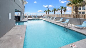 A swimming pool with lounge chairs, a wooden fence, and palm trees. - Beach Front Condo! Newly Renovated! Awesome views! Private Balcony! (Gulf Shores)