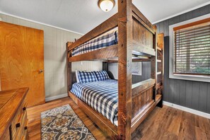 A bunk bed with a checkered bedspread, a wooden headboard, and a window with blinds. - 58 Powderidge, Snowshoe, WV - Cozy Chalet (Snowshoe)