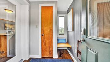 Ein Flur mit einer Holztür, einer Bank und einem Fenster mit Jalousien.