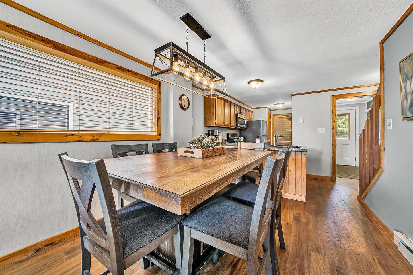 A modern kitchen with wooden cabinetry, a central island, and a dining area with a wooden table and chairs.