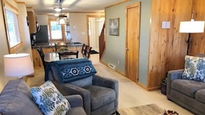 A living room with two sofas, a coffee table, and a dining area in the background. - 11 Powderidge, Snowshoe, WV - Slopeside Serenity (Snowshoe)